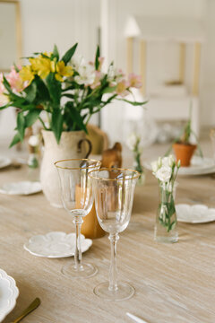 Dining table with beautiful setting, glasses and fresh flowers