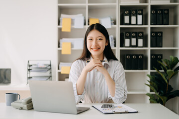 Asian businesswoman working in the office with working notepad, tablet and laptop documents in...