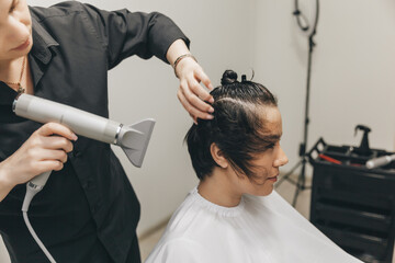 Close-up of the hands of a hairdresser drying women's hair with a hairdryer. short haircut and styling