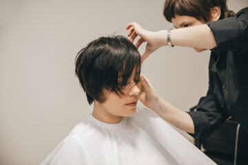 The hairdresser is styling the hair of a female client in the salon. short haircut