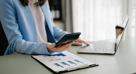 Business woman sitting front tablet ,laptop computer with financial graphs and statistics on monitor.at modern office