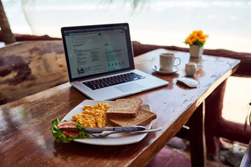 Cafe food, laptop or breakfast by a beach for remote workspace in the morning with connection. Desk, seaside restaurant or table in coffee shop for digital blog online with brunch meal or lunch