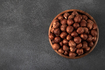 View of a bowl full of hazelnuts on a black background
