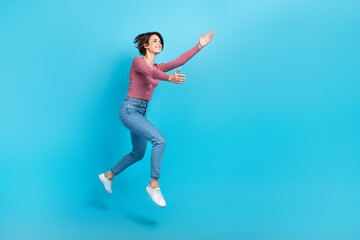 Fototapeta na wymiar Full body profile portrait of cheerful nice lady jump run raise hands catch empty space isolated on blue color background