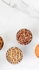 Legumes in glass jars top view on white background. Vegetable protein, healthy eating. Copy space