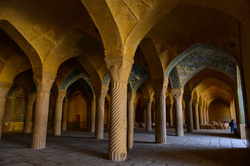 "Vakil" mosque praying hall with spiral pillars of stones and roof tiling illuminated with sunlight located in Shiraz; Iran