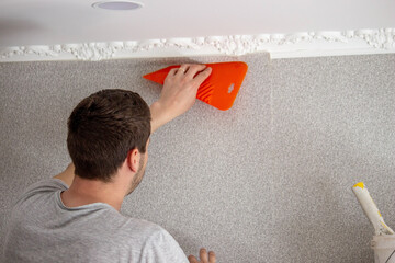 A man glues wallpaper, repairs the house.