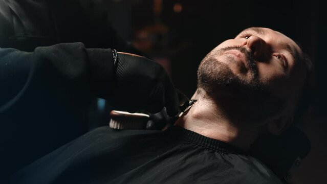 Male barber hands shaving customer beard styling use electric trimmer machine and comb closeup