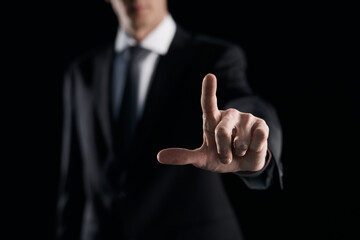 Focused businessman pointing with finger on dark background