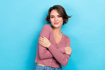 Photo of shiny pretty lady wear pink cardigan smiling embracing herself isolated blue color...