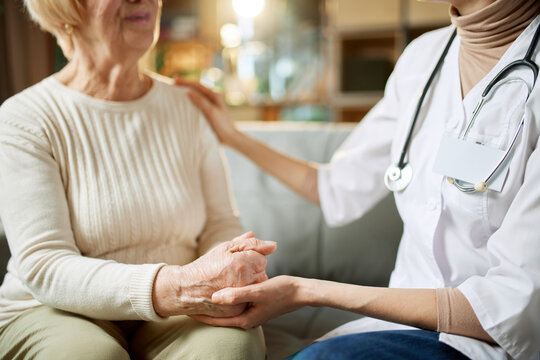 Cropped image of female doctor giving support and hope to her elderly patient. Woman holding hand of senior lady. Concept of medical care, medicine, illness, health care, profession