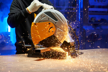 A worker cuts a metal part on a cutting disc machine. discs are flying apart