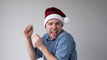 The happy European young man in a New Year's hat joyfully dances at the party