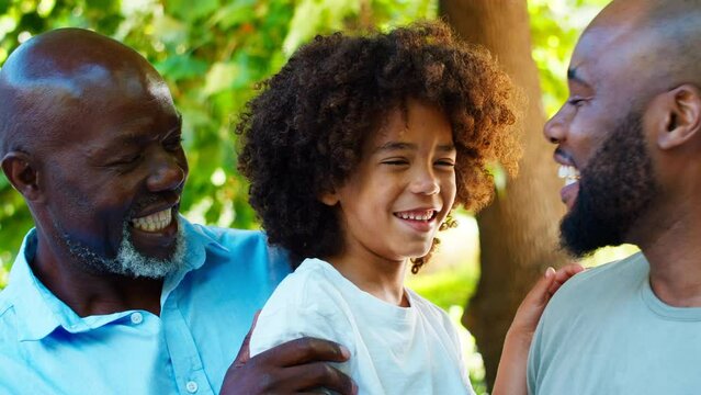 Portrait of smiling multi-generational male family in garden at home together - shot in slow motion