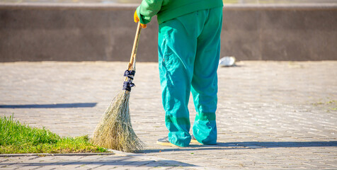 The janitor cleans the city street with a broom in the city. Street cleaning service. A worker...