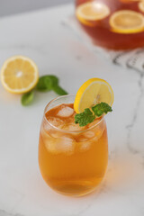 Iced tea with lemon and mint in a glass and in a jug. Summer drinks.