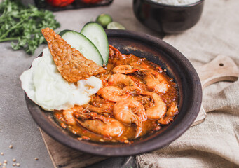 Udang sambal gami or spicy prawn is Traditional food from Indonesia. served on plate with a bowl of rice and vegetables. Isolated gray background