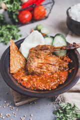 Bebek goreng sambal gami or spicy fried duck is Traditional food from Indonesia. served on plate with a bowl of rice and vegetables. Isolated gray background