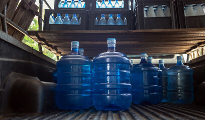A plastic big bottle of blue gallons on the back of the pickup truck of purified drinking water inside the production line to prepare for sale. Water drink factory, small business