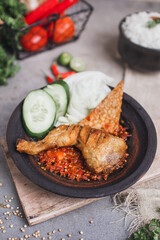Ayam sambal gami or spicy fried chicken is Traditional food from Indonesia. served on plate with a bowl of rice and vegetables. Isolated gray background