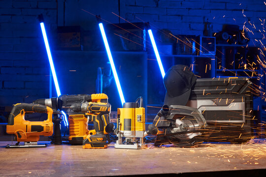 electric power tools are on the workbench in the workshop: a jigsaw, a drill, a hammer drill, a screwdriver, a milling cutter, a circular saw. sparks fly from the side