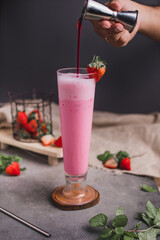 Glass of fresh strawberry milkshake, smoothie and fresh strawberries on dark and wooden background. Healthy food and drink concept.