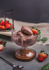 Ice cream sundae in sundae cup or glass with fresh strawberries isolated on black background