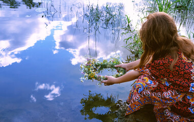 girl near river and holding flower wreath, abstract natural background. Esoteric ritual for summer solstice, wiccan Litha sabbat. ceremony on Midsummer. pagan slavic holiday Ivan Kupala. witchcraft