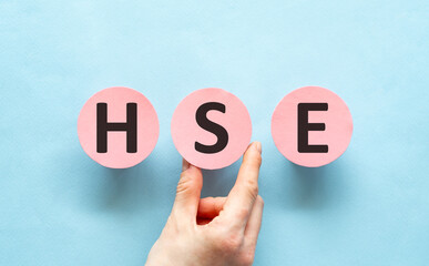 Hand writing HSE - Health Safety Environment acronym with marker on pink paper, concept background