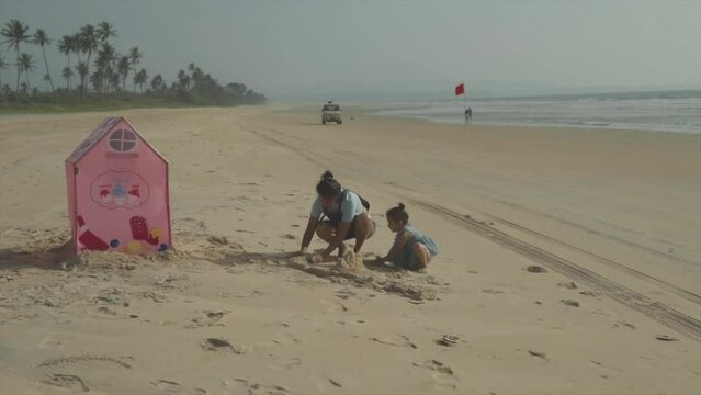 Nostalgic moment of a mother and daughter building sandcastles together.