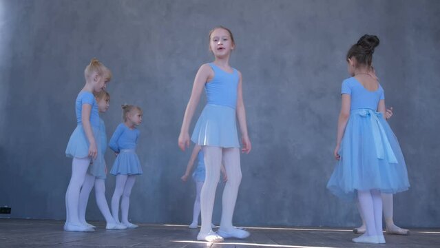 A girls dancer in a ballet school is learning to dance. Little ballerinas in training in a dance costume. Children's ballet school. 4K