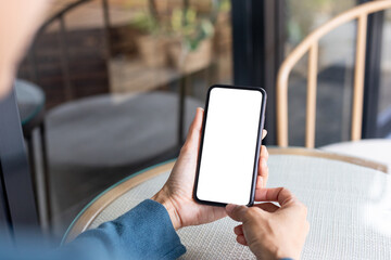 cell phone blank white screen mockup.hand holding texting using mobile on desk at office.background...