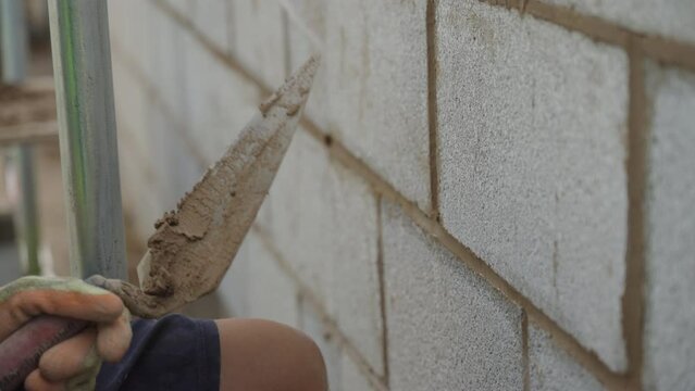 A bricklayer points up a concrete block wall