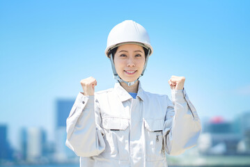 ガッツポーズをする作業服姿の女性