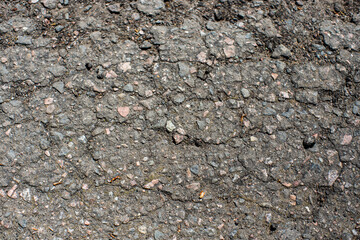 A network of black cracks on the asphalt surface. Road texture with weathered surface, showcasing...