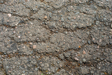 A network of black cracks on the asphalt surface. Road texture with weathered surface, showcasing the effects of time and wear