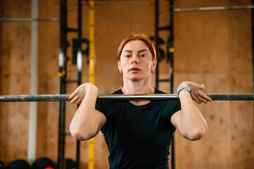 Naklejka premium Lifting the barbell. Beautiful strong woman is in the gym