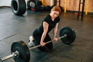 Fototapeta na wymiar Leaning on the barbell. On the floor. Beautiful strong woman is in the gym