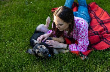 Naklejka na ściany i meble Beautiful young woman playing with her young dog in the park outdoors. Life style portrait.