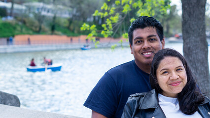 young pregnant couple sitting by the lake on an autumn afternoon