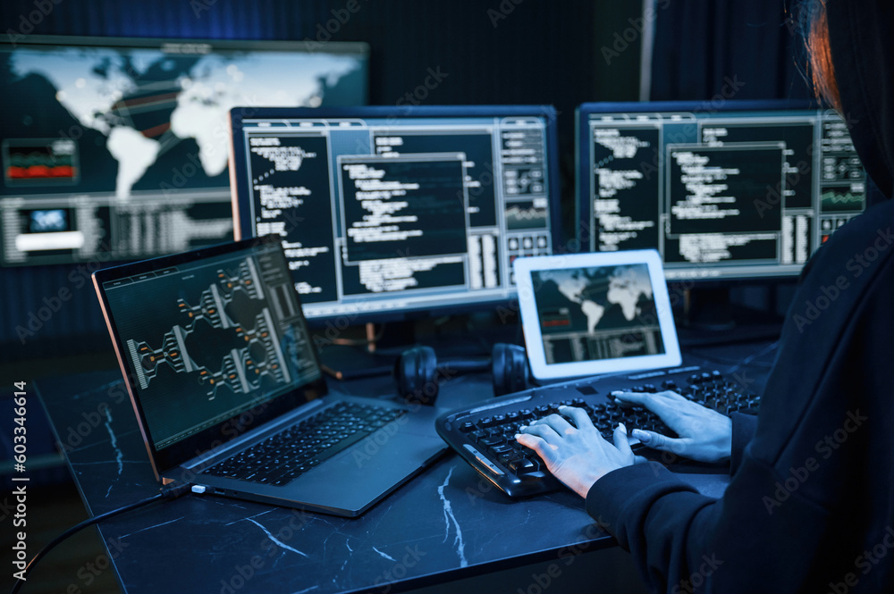 Aufkleber information on screens. young professional female hacker is indoors by computer with lot of informat