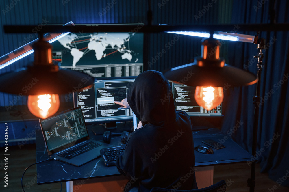Poster information on screens. young professional female hacker is indoors by computer with lot of informat