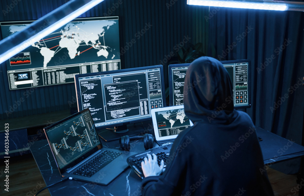 Poster information on screens. young professional female hacker is indoors by computer with lot of informat