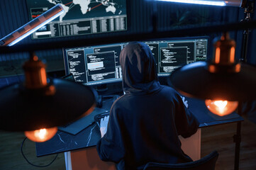 Light bulbs. Young professional female hacker is indoors by computer with lot of information on...