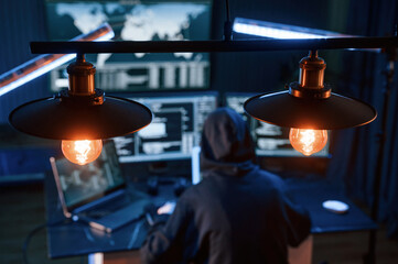 Light bulbs. Young professional female hacker is indoors by computer with lot of information on displays