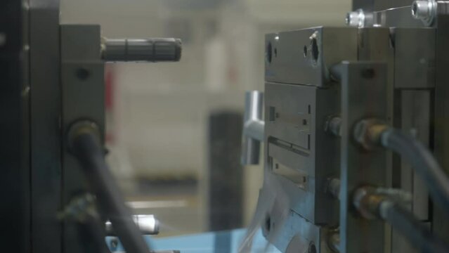 Factory machine shaping the plastic material on the conveyor production line. Manufacturing machine turns plastic into desired shapes. Machine creates various plastic shape at the facility.
