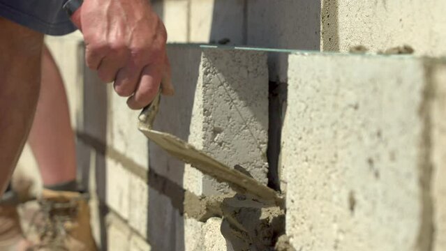 UK - bricklayer puts mortar onto a wall ready for the last block