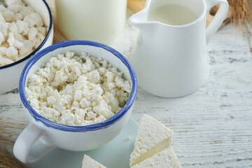 Shavuot jewish holiday celebration. Kosher fresh dairy products milk and cheese, ripe wheat, cream on white wooden background. Dairy products over white wooden background. Shavuot concept. Top view.
