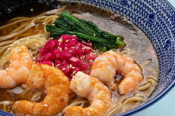 Portion of ramen noodle soup with shrimp on blue background