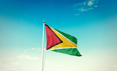 Waving Flag of Guyana  in Blue Sky. The symbol of the state on wavy cotton fabric.